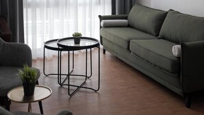 Un salon moderne avec un canapé vert, une table basse ronde et une plante en pot.