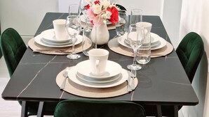 A dining table set with white plates, bowls, and glasses, accompanied by a vase of flowers. - Leeds City Escape - Stylish Apartment (Leeds)