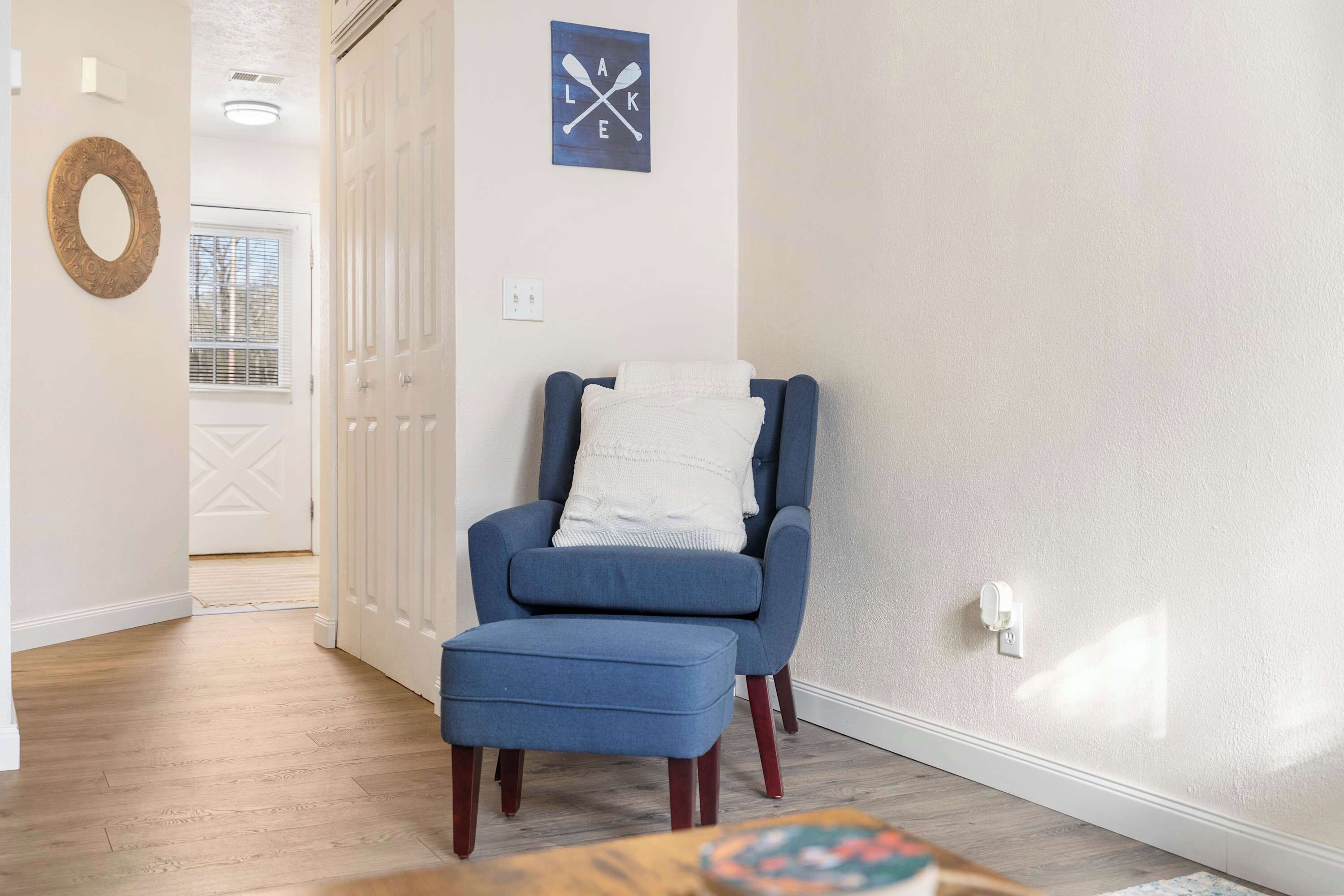 Ein Zimmer mit blauem Sessel, weißem Kopfkissen und Holzboden.