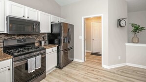 A modern kitchen with stainless steel appliances, white cabinetry, and a wooden floor. - Poolside Paradise Near the Ark (Walton)