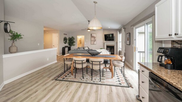 A modern kitchen with a dining area, featuring a wooden table, chairs, and a hanging light fixture. - Poolside Paradise Near the Ark (Walton)