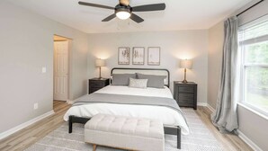 A bedroom with a bed, bedside tables, a ceiling fan, and a window with curtains. - Poolside Paradise Near the Ark (Walton)