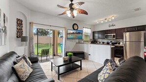 A modern living room with a black leather sofa, a coffee table, and a ceiling fan. - Mickeys Oasis At Regal Palms (Davenport)