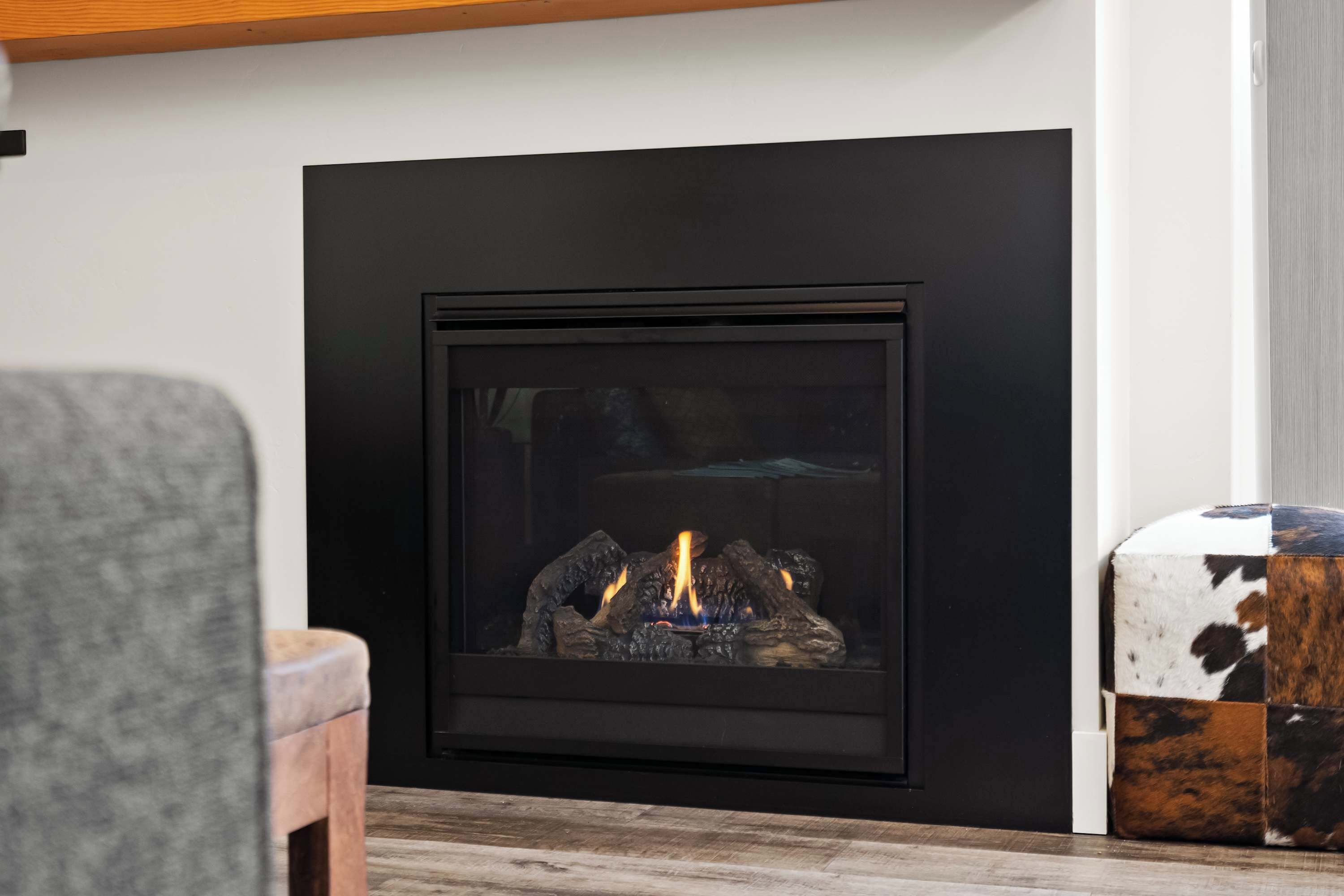 A modern fireplace with a black surround, a visible fire, and a rustic side table.