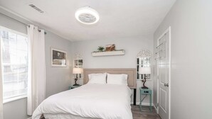A bedroom with a bed, bedside tables, a nightstand, a wall-mounted shelf, and a door. - Arkstone Retreat - 3 in 1! Only 4 min to the Ark! (Williamstown)