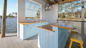 A waterfront kitchen with a large window, wooden counter, and a fan.