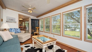 A living room with a sofa, a coffee table, and large windows with blinds.