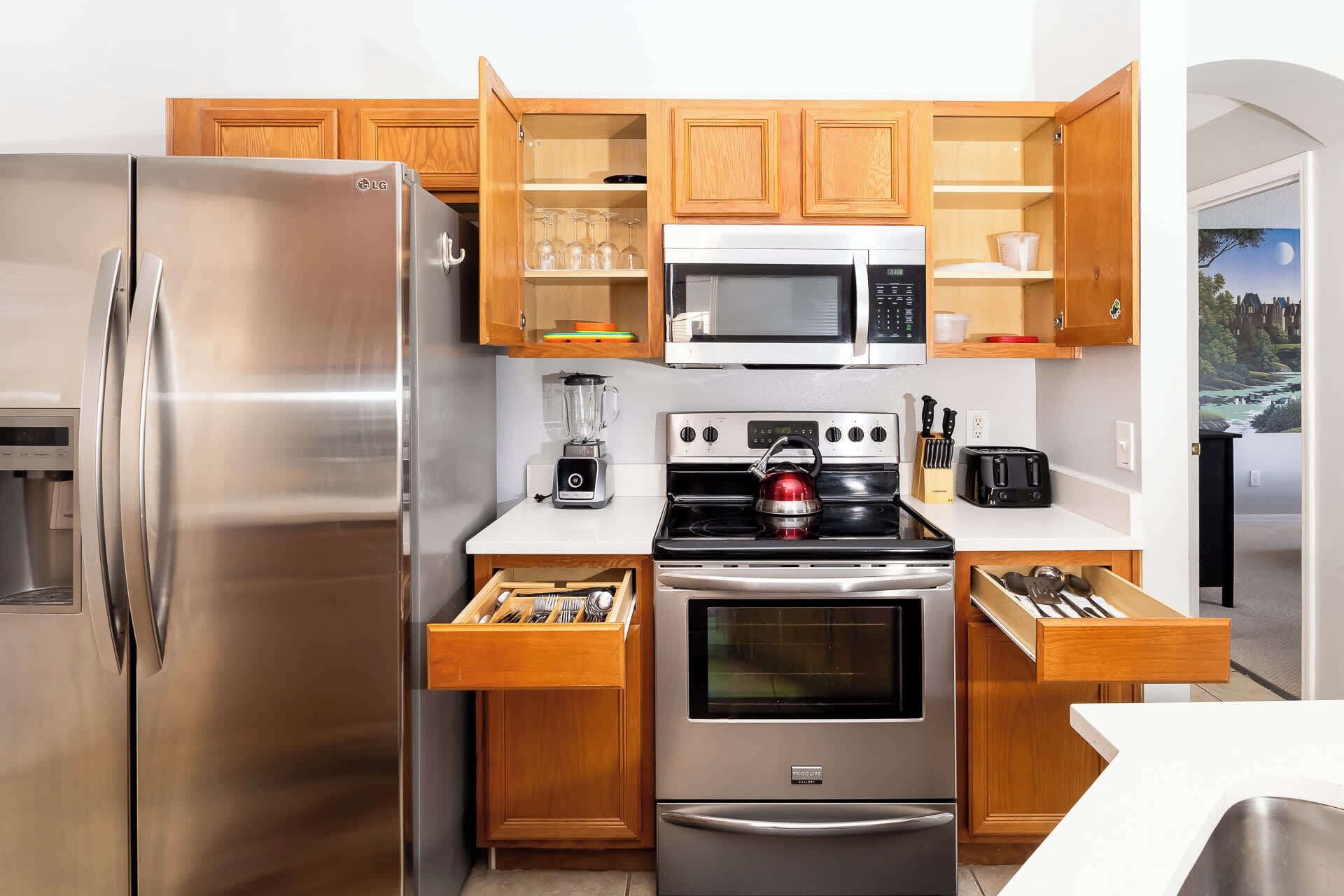 A compact kitchen with a stainless steel refrigerator, microwave, stove, and oven.