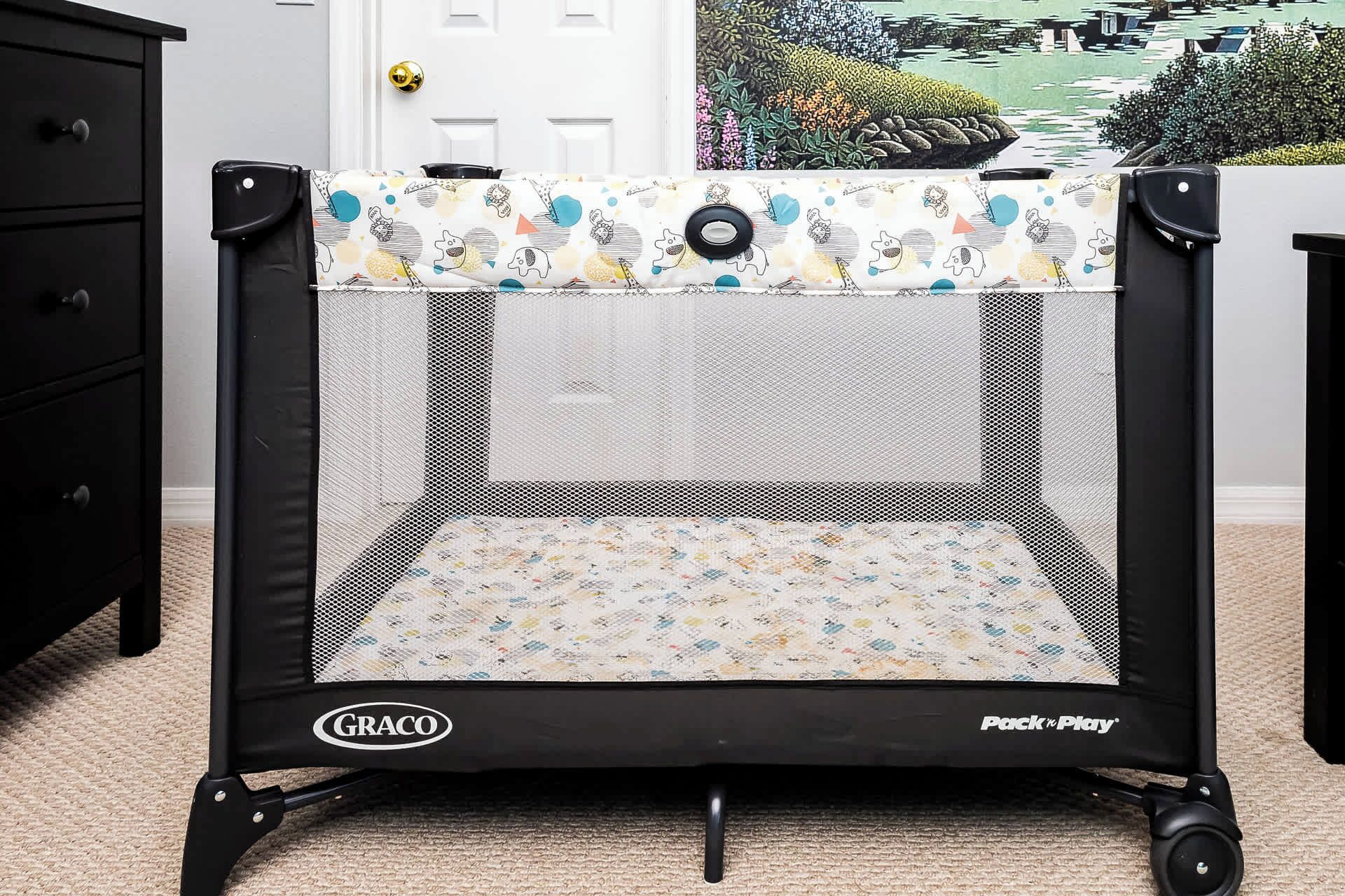 A portable playpen with a mesh top and a patterned floor, labeled 'GRACO Pack 'n Play.'