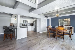 A spacious kitchen with white cabinets, a dining area with wooden chairs, and a large window. - For the View Lakeside Launchpad! Great Location (Gravois Mills)