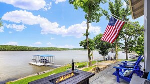 A lakeside patio with a fire pit, outdoor seating, and an American flag. - For the View Lakeside Launchpad! Great Location (Gravois Mills)
