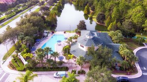 A residential area with a swimming pool, a house with a sloped roof, and a lake.