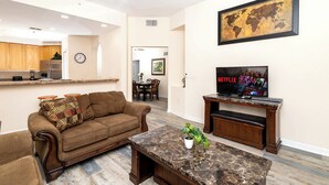 A living room with a brown sofa, a coffee table, and a TV displaying the Netflix logo.