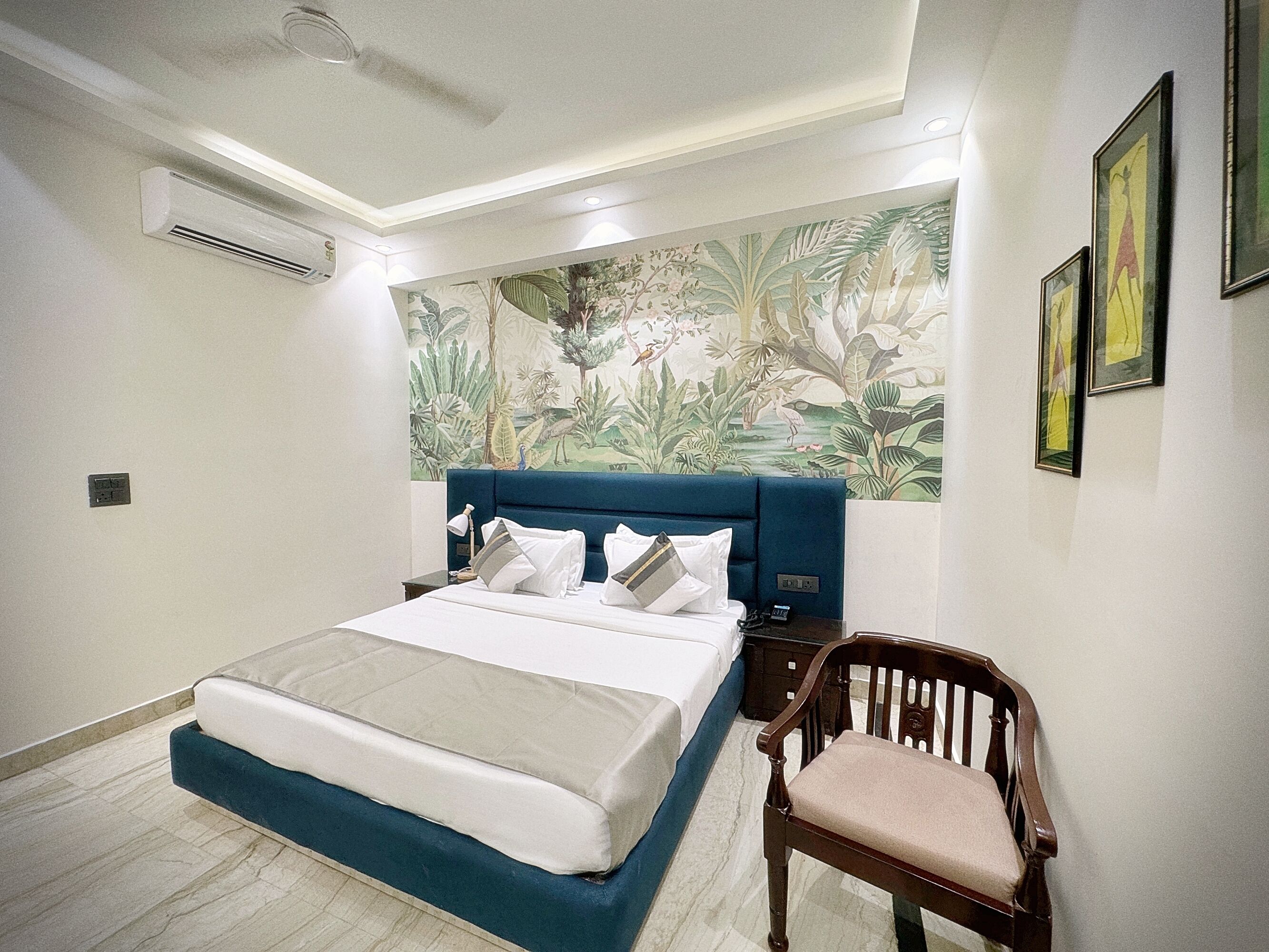 A bedroom with a large bed, a nightstand, a chair, and a mural on the wall.