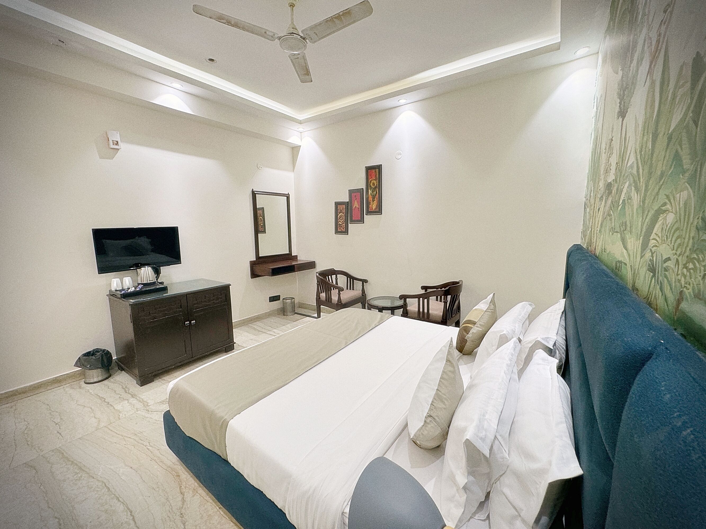 Une chambre à coucher comprenant un lit, un téléviseur, une commode, une chaise et un ventilateur de plafond.