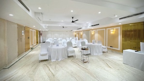 Una sala conferenze con sedie e tavoli bianchi, ventilatori a soffitto e illuminazione a incasso.