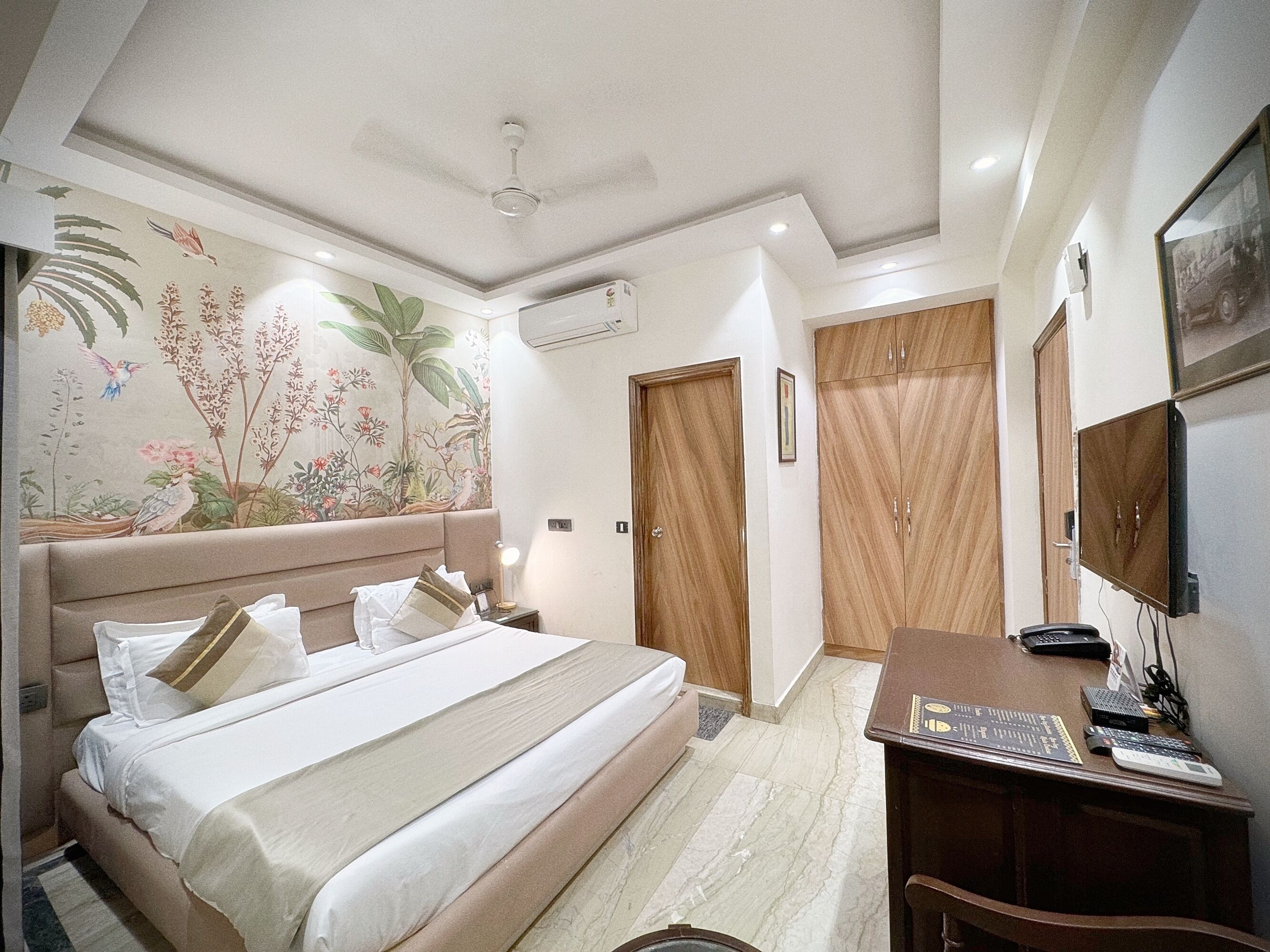 Una habitación de hotel con una cama, un escritorio con ordenador, un armario y un ventilador de techo.