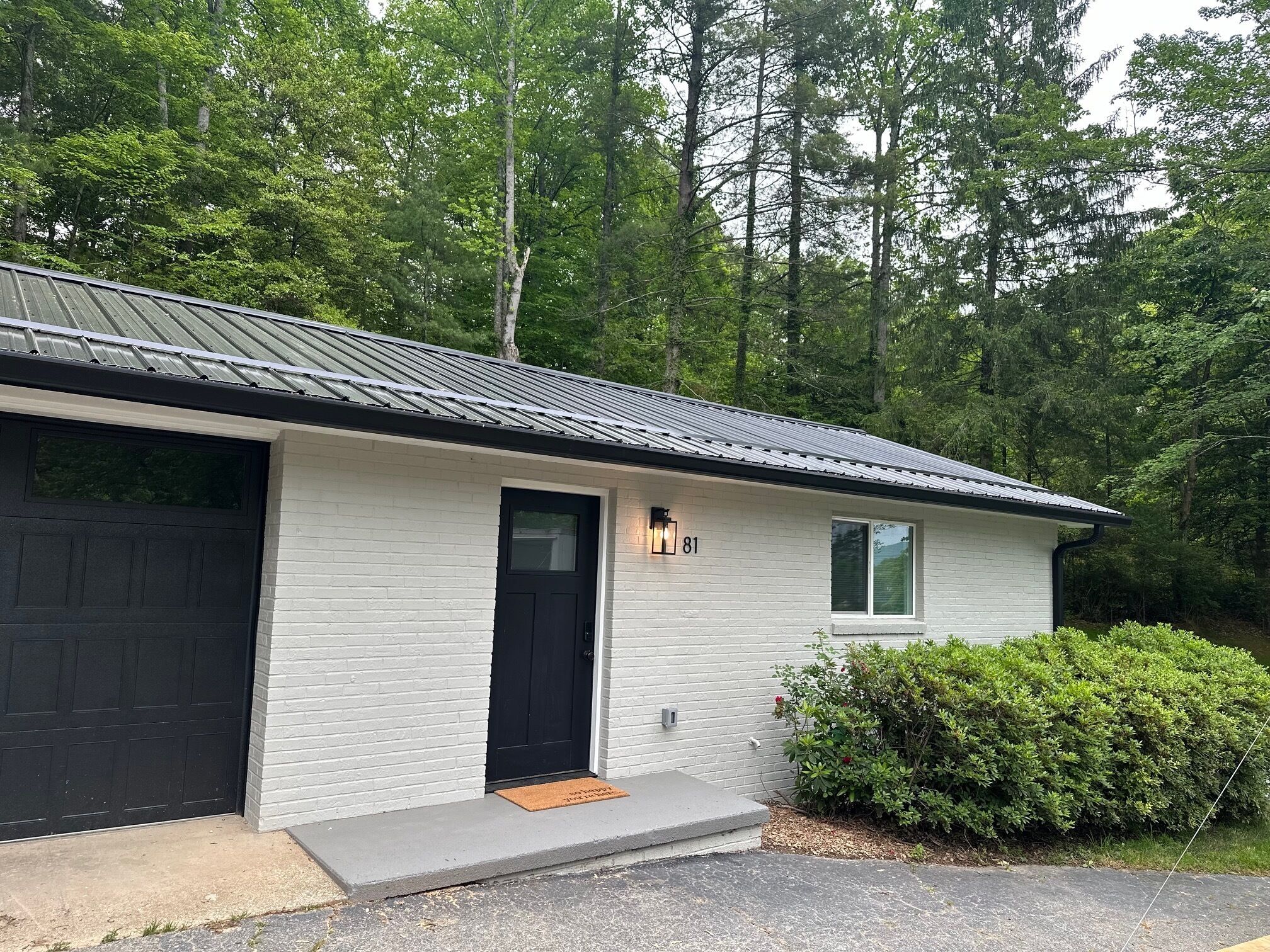 A single-story building with a black garage door, a black front door, and a small window.