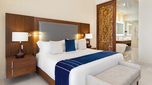 A modern hotel room with a large bed, two bedside tables with lamps, a wooden headboard, and a view into the bathroom. - Beach front property, excellent service,  and food.Unforgettable experience.  (San José del Cabo)