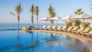 An infinity pool with lounge chairs and umbrellas, palm trees, and a view of the ocean. - Beach front property, excellent service,  and food.Unforgettable experience.  (San José del Cabo)