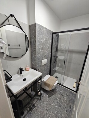 Kombinasi shower/bathtub, pengering rambut, handuk, dan tisu toilet