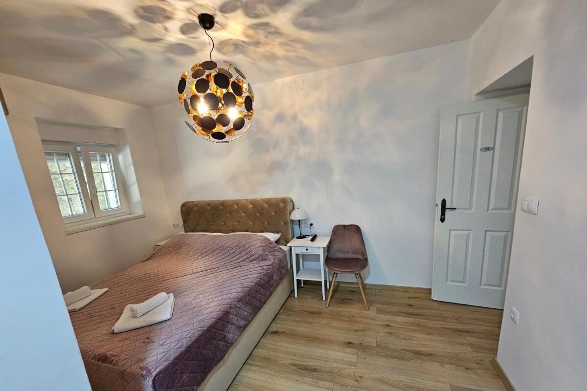A bedroom with a bed, a desk, a chair, and a unique ceiling light fixture.