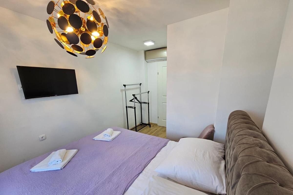 A modern hotel room with a bed, a flat-screen TV mounted on the wall, and a unique spherical light fixture.
