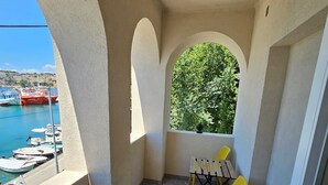 A balcony with a yellow chair, a view of boats, and a window with greenery. - Villa Gaj (Omisalj)