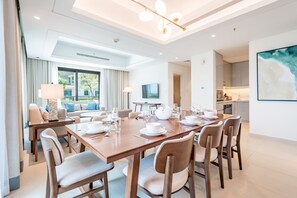 A modern hotel room with a dining area, a sofa set, a kitchen, and a large window. - Seafront 4BR Apartment with Assistant Room in The Address Fujairah Residences Block B, Fujairah (Fujairah)
