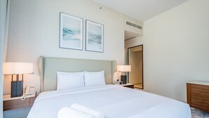 A hotel room with a large bed, two bedside lamps, a phone, and a mirror.