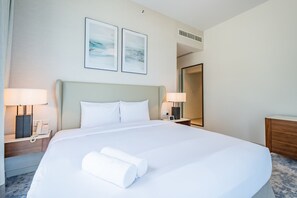 A hotel room with a large bed, two bedside lamps, a phone, and a mirror. - Seafront 4BR Apartment with Assistant Room in The Address Fujairah Residences Block B, Fujairah (Fujairah)