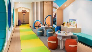 A children's play area with colorful mats, seating, and educational toys.