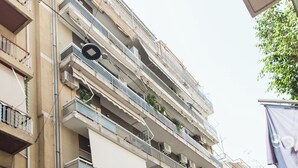 Un immeuble à plusieurs étages, doté de balcons, d’un auvent vert et d’une voiture garée.