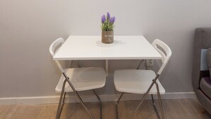 Une table blanche avec deux chaises, une petite plante en pot et un sous-verre blanc.