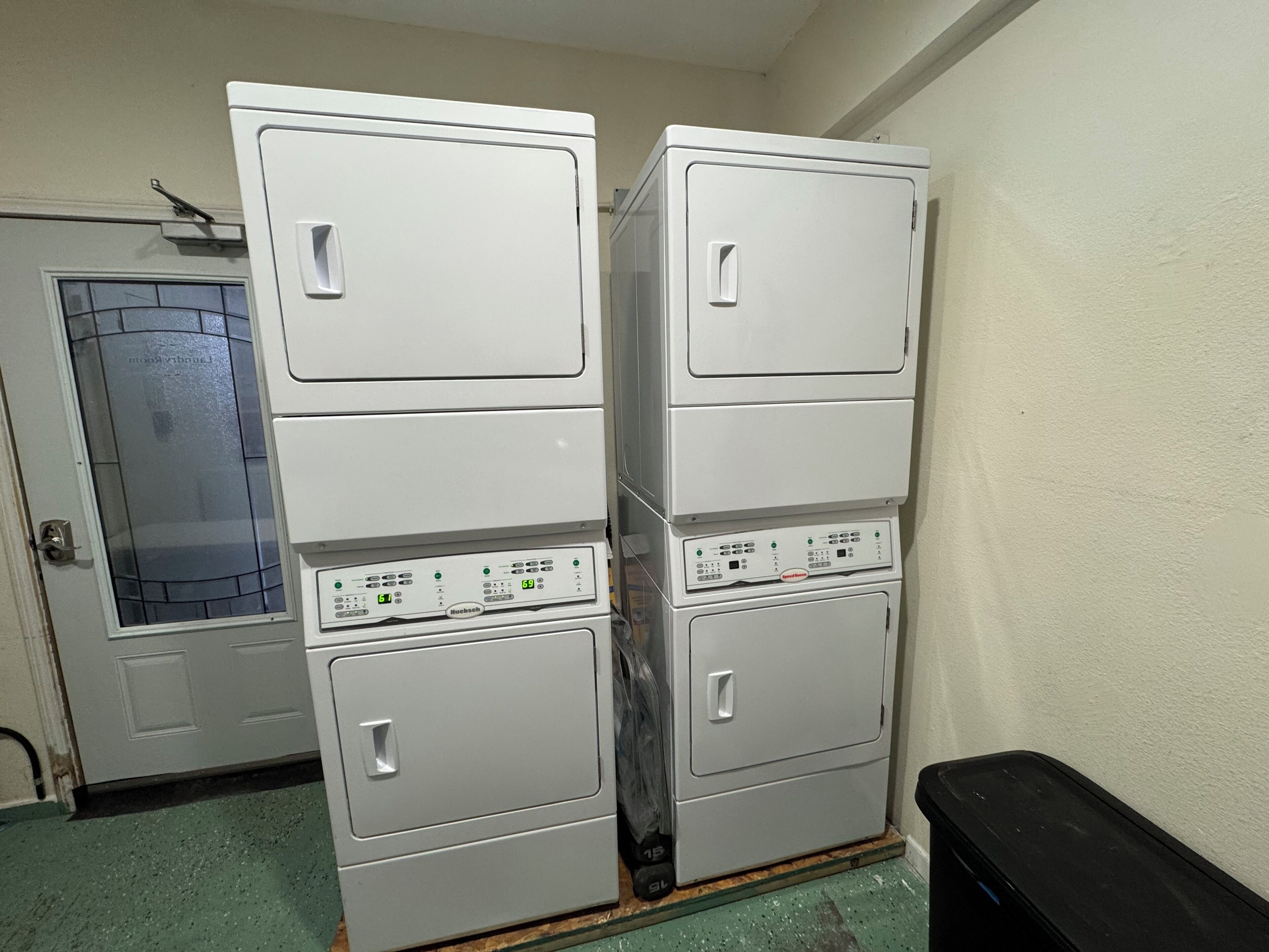 Un cuarto de lavandería con lavadoras y secadoras apiladas.