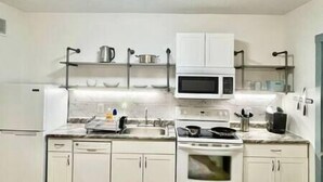 Una cocina con gabinetes blancos, un microondas, una estufa y un lavaplatos.