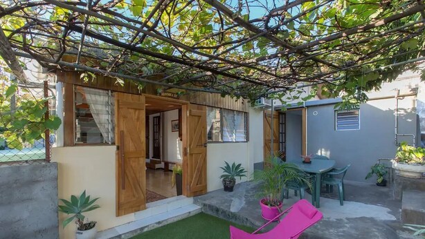 Une agréable terrasse extérieure agrémentée d’une pergola en bois, d’une petite table avec des chaises et de plantes en pot.