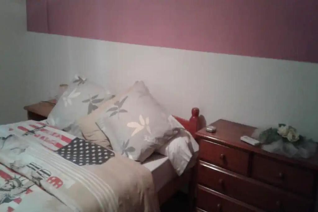 A bedroom with a bed, pillows, a dresser, and a nightstand.