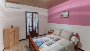 Une chambre à coucher comprenant un lit, une armoire, une table de chevet et une fenêtre avec des rideaux.