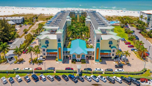 A resort hotel with a central courtyard, multiple balconies, and a beach view.