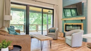 A spacious living room with a large window, a fireplace, and a wooden floor.