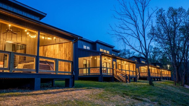 A modern wooden cabin with large windows and a deck.