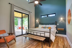 A bedroom with a bed, a bench, a chair, a ceiling fan, and a view of the outdoors. - Still Waters on Watauga River (Johnson City)