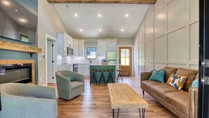A spacious living area with a sofa, chairs, a coffee table, and a kitchen in the background.