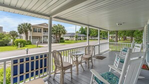 A covered porch with a table and chairs, a railing, and a view of a residential street. - 5-Bedroom Large Home in Windy Hill -Jus' Yungins (North Myrtle Beach)