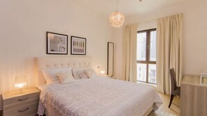 A bedroom with a bed, nightstands, a desk, a hanging light fixture, and two framed pictures on the wall. - Walking Distance to Burj Khalifa! (Old Town Dubai)