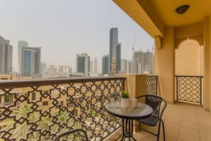 A balcony with a patterned fence, a small table with a potted plant, and chairs.
