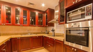 A kitchen with wooden cabinets, a stainless steel oven, and a microwave. - Walking Distance to Burj Khalifa! (Old Town Dubai)