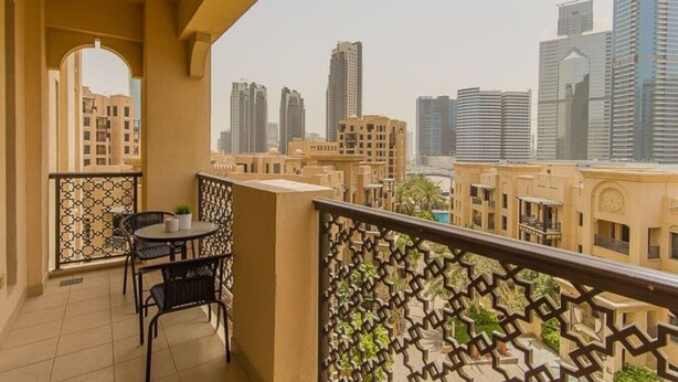A balcony with a table and chairs, a patterned railing, and a cityscape view. - Walking Distance to Burj Khalifa! (Old Town Dubai)
