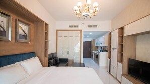 A hotel room with a large bed, a TV, a desk, and a wardrobe.